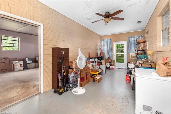 Misc room with brick wall, concrete flooring, and ceiling fan
