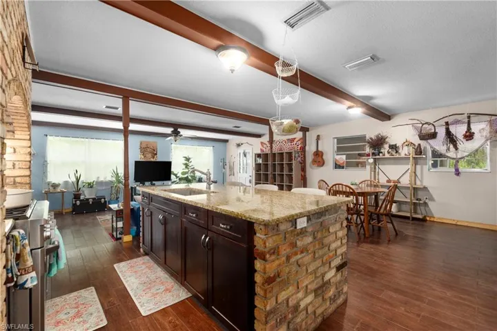 Kitchen featuring a wealth of natural light, sink, beamed ceiling, and a kitchen island with sink