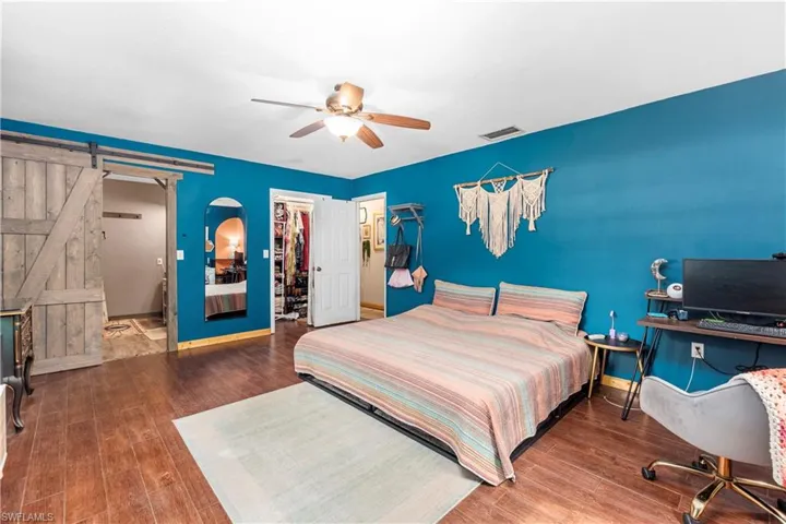 Bedroom with a closet, ceiling fan, hardwood / wood-style flooring, a walk in closet, and a barn door