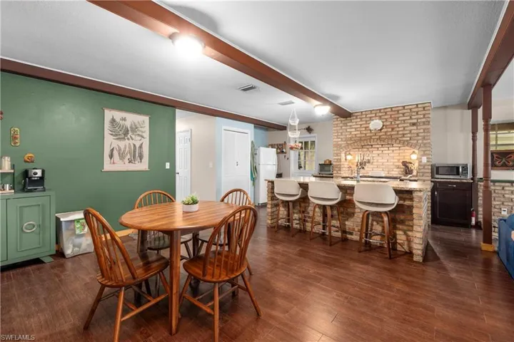Dining space with beam ceiling, dark wood-type flooring, and sink