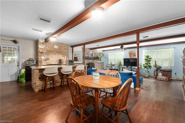 Dining room featuring a fireplace, dark hardwood / wood-style floors, ceiling fan, and beam ceiling
