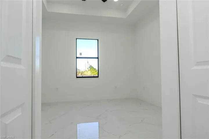Unfurnished room with a raised ceiling and marble finish flooring