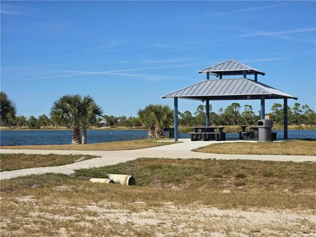 Surrounding community with a gazebo, a water view, a patio, and a lawn