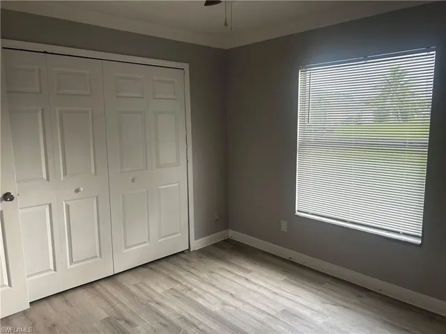 Unfurnished bedroom featuring crown molding, a closet, light wood-type flooring, and ceiling fan