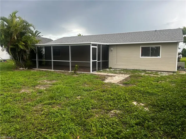 Rear view of house featuring a sunroom and a yard
