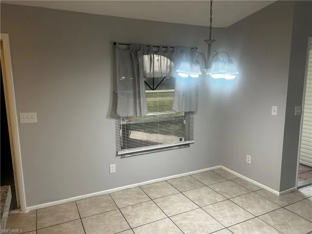 Unfurnished dining area featuring an inviting chandelier and light tile flooring