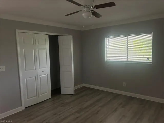 Unfurnished bedroom with ceiling fan, a closet, and dark wood-type flooring