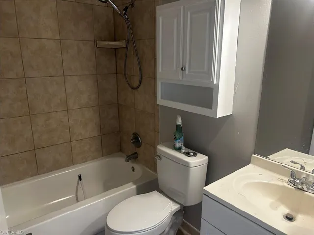 Full bathroom featuring tiled shower / bath combo, vanity, and toilet