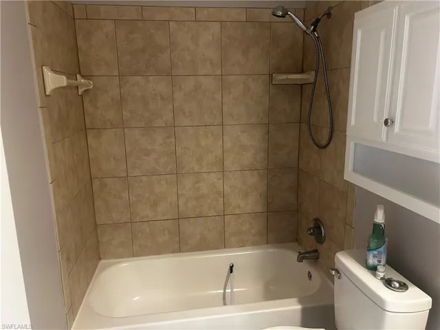 Bathroom with tiled shower / bath and toilet