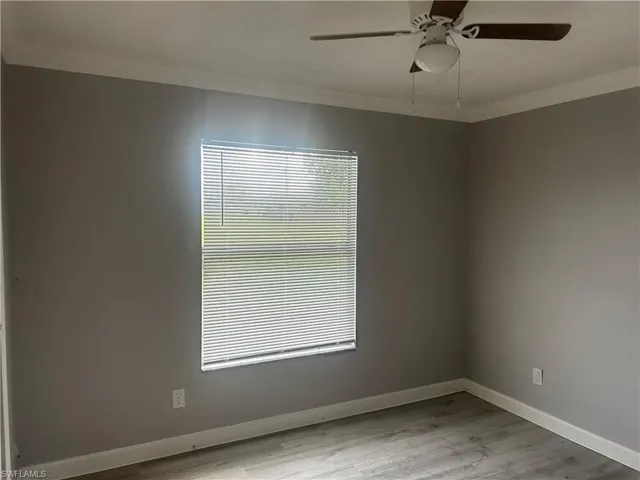 Empty room featuring ceiling fan, light wood-type flooring, and crown molding