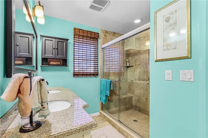 Bathroom featuring a shower stall and double vanity