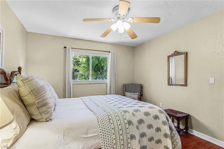 Bedroom with wood finished floors, a textured wall, a ceiling fan, and a textured ceiling