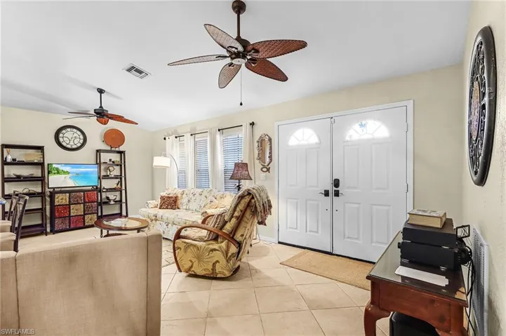 Living area with vaulted ceiling, a ceiling fan, and light tile patterned floors