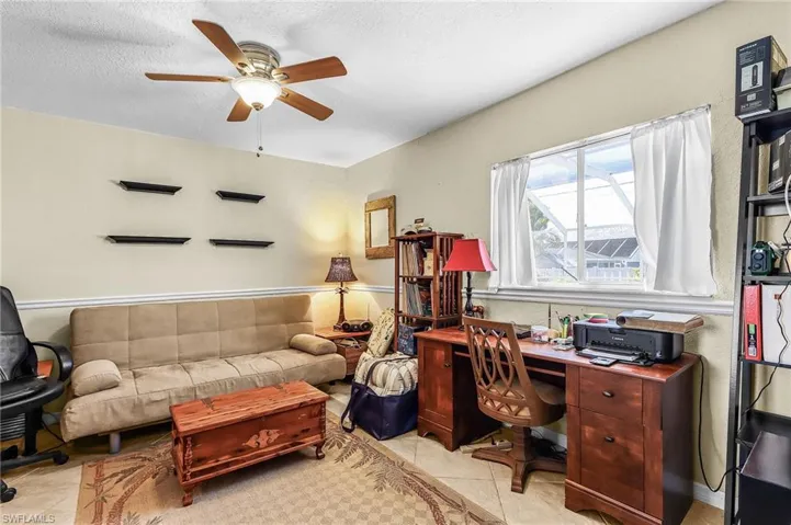 Office area featuring ceiling fan, light tile patterned floors, and a textured ceiling