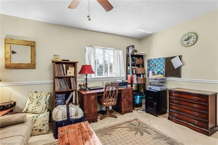 Office area featuring ceiling fan, light tile patterned flooring, a textured wall, and a textured ceiling