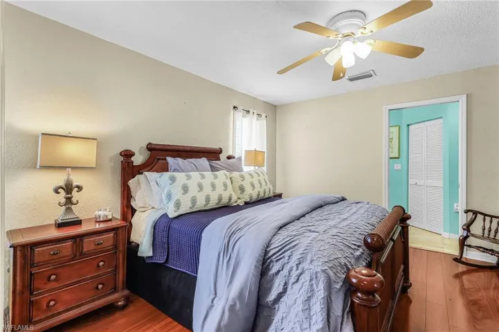 Bedroom featuring wood finished floors, ceiling fan, a textured wall, and a textured ceiling
