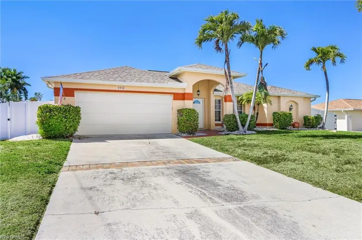 View of front facade featuring stucco siding, concrete driveway, an attached garage, and a front yard