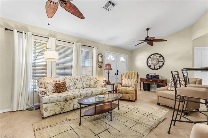 Living area with ceiling fan, lofted ceiling, and light tile patterned flooring