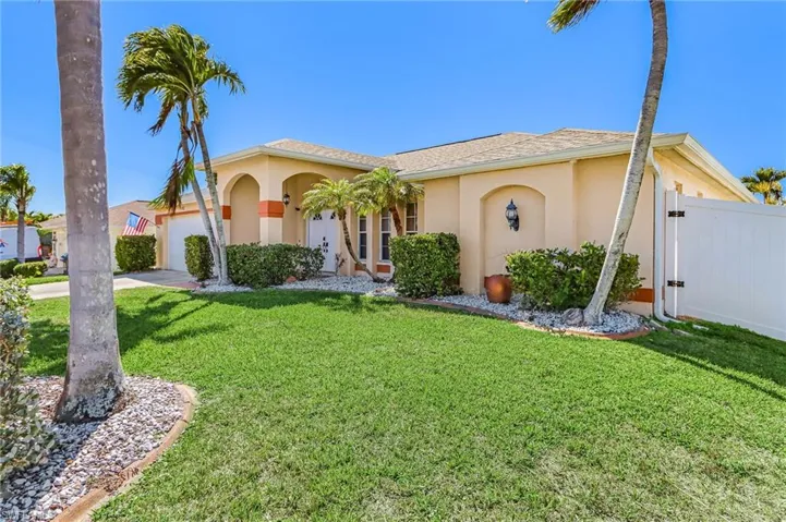 View of front of house featuring an attached garage, stucco siding, a front yard, a gate, and concrete driveway