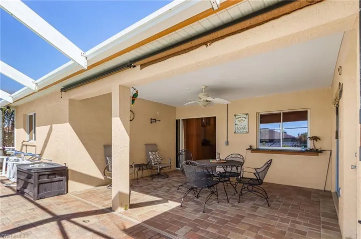 View of patio featuring outdoor dining area, ceiling fan, and glass enclosure