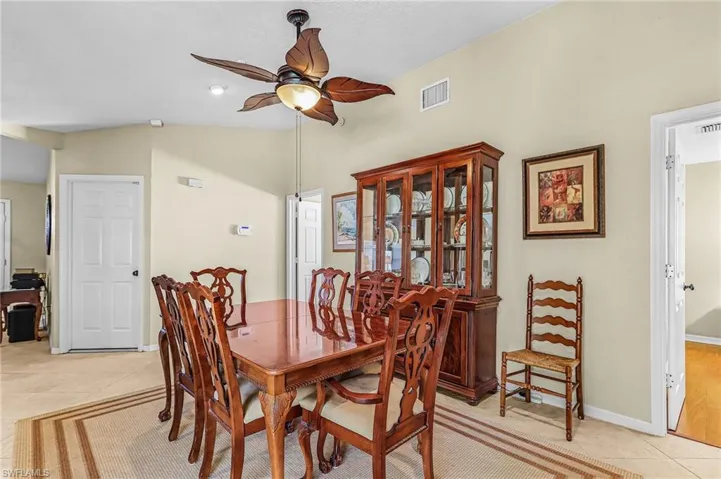 Dining space with light tile patterned floors, a ceiling fan, and lofted ceiling