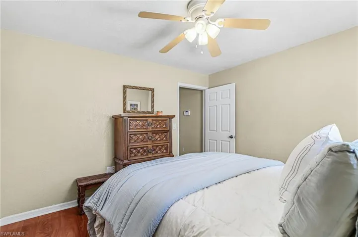 Bedroom featuring wood finished floors, ceiling fan, and a textured wall