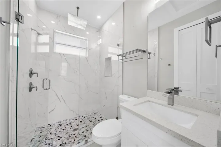 Full bath featuring vanity and a marble finish shower