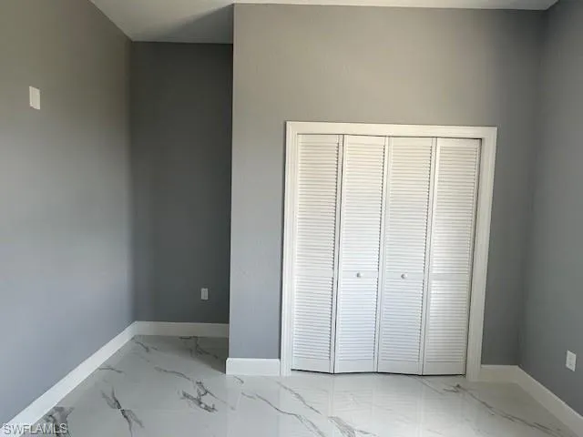 Unfurnished bedroom featuring a closet and light tile floors