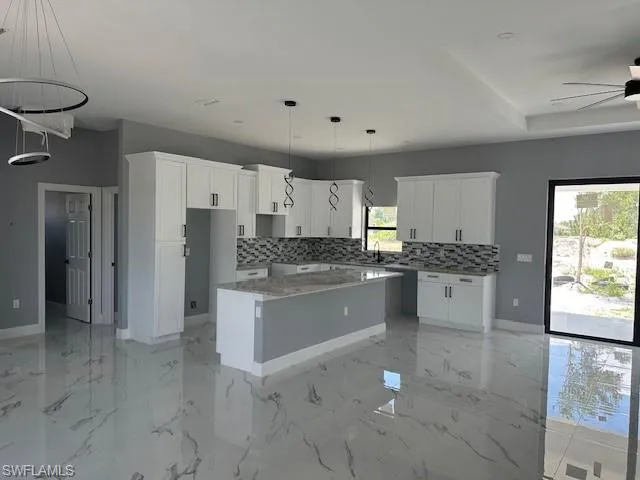 Kitchen with a center island, ceiling fan, light tile floors, and plenty of natural light