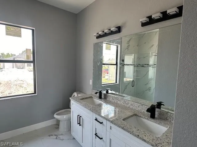 Bathroom featuring tile floors, dual bowl vanity, plenty of natural light, and toilet