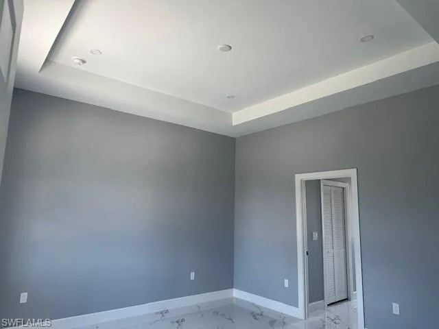Tiled empty room featuring a raised ceiling