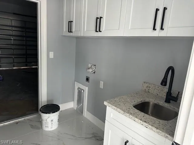 Laundry area featuring cabinets, sink, hookup for an electric dryer, and tile flooring
