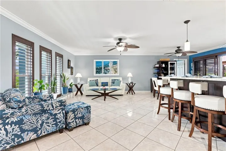 Spacious open-concept living area featuring tile flooring, multiple ceiling fans, and an integrated counter-height dining bar