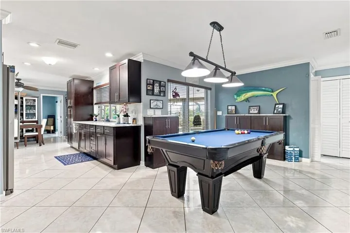 Open-concept space featuring large format tile flooring, dark wood-finish cabinetry, built-in storage, and a triple pendant light fixture