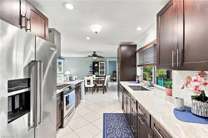 Kitchen featuring dark wood-finish cabinetry, light-toned countertops, stainless steel appliances, and tile flooring