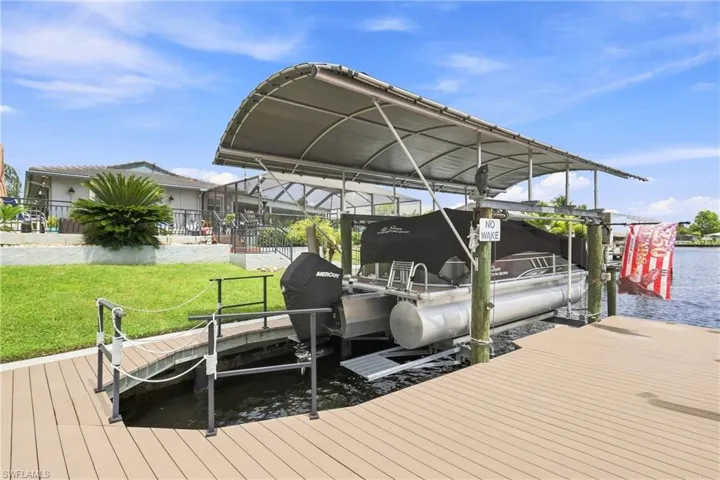 Expansive waterside deck with a boat lift, covered boat slip, and direct water access