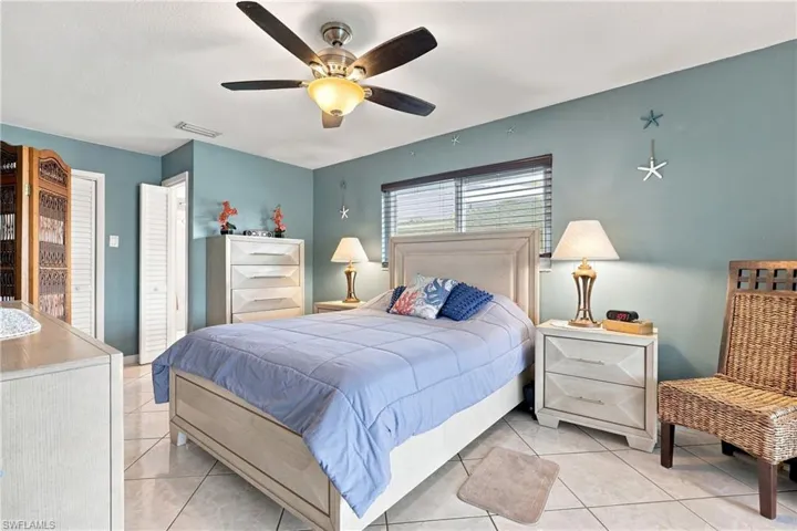 Ceiling fan with integrated lighting, tile flooring, window with blinds, and white louvered bifold doors