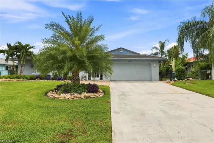 Single-story residence featuring a two-car garage, mature landscaping, concrete driveway, and decorative exterior accents