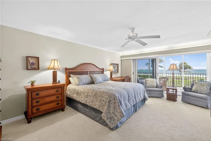 This bedroom features neutral-toned walls, a ceiling fan, and carpeted flooring