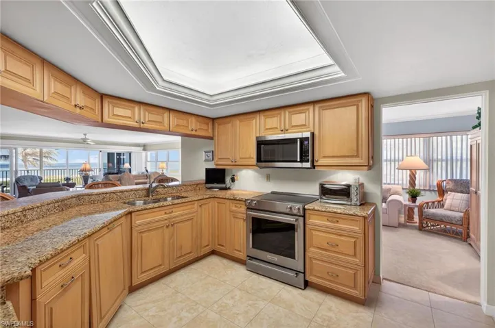 Well-appointed kitchen featuring light wood cabinetry, granite countertops, stainless steel appliances, and tile flooring