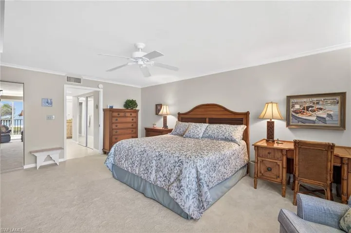 Primary Bedroom features light-colored carpeting, a ceiling fan, and a view of the outdoors through a doorway