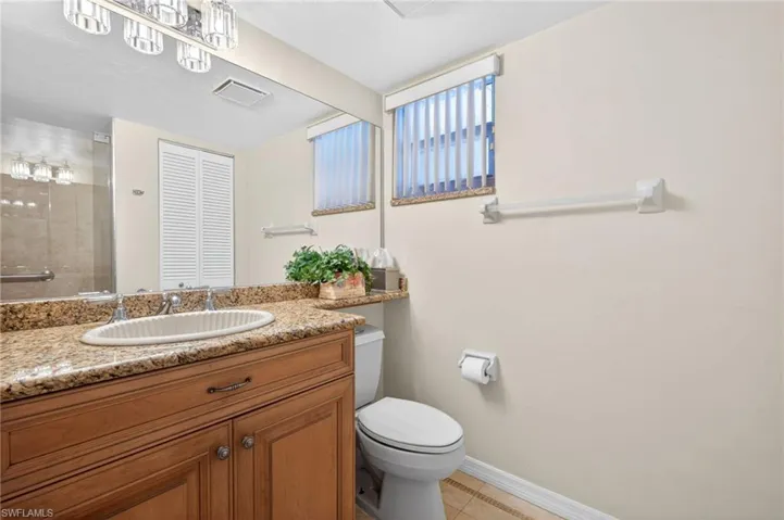 The bathroom features a vanity with a light brown cabinet, a granite countertop, and a white oval sink