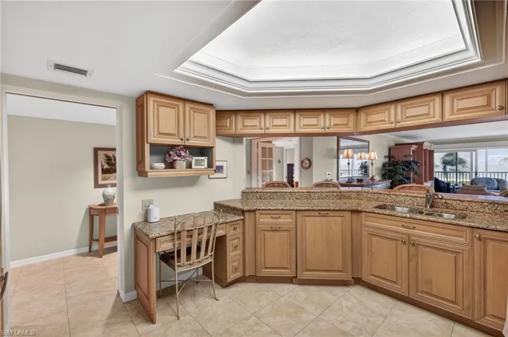 The kitchen features extensive wood cabinetry, granite countertops, and a double basin sink