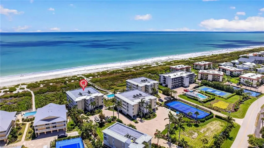 Aerial view of the community, featuring direct views of the ocean, a white sand beach, and several tennis courts