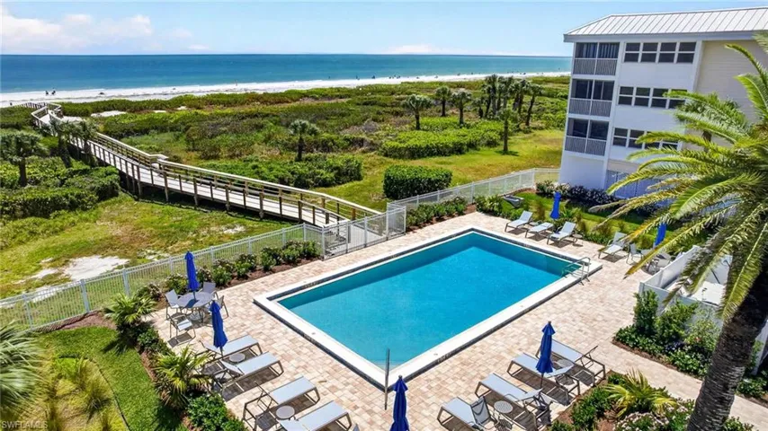 The property features a swimming pool with a paved deck, surrounded by landscaping and a white fence