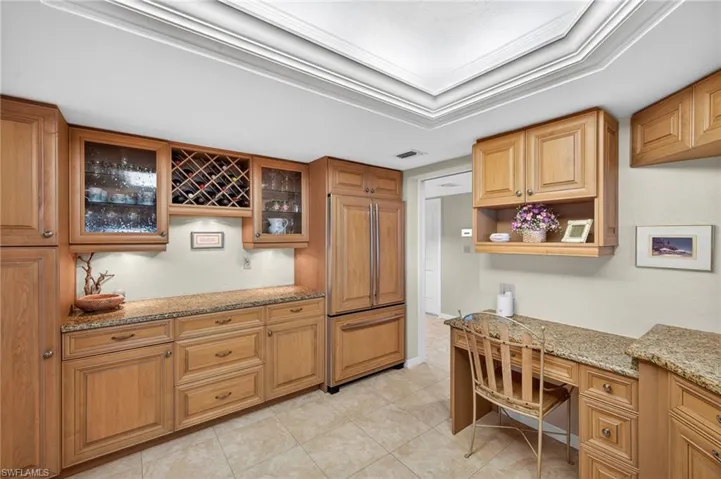 The kitchen features extensive wooden cabinetry, granite countertops, and tiled flooring