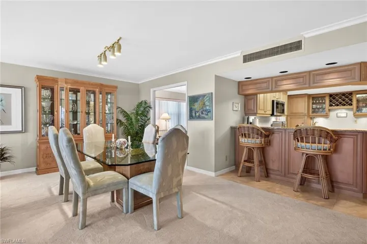 Inviting dining area featuring a glass-top table, upholstered chairs, and a built-in display cabinet