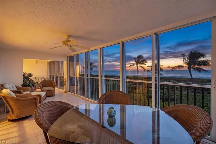 Sunroom with tile flooring and a ceiling fan, offering broad ocean views
