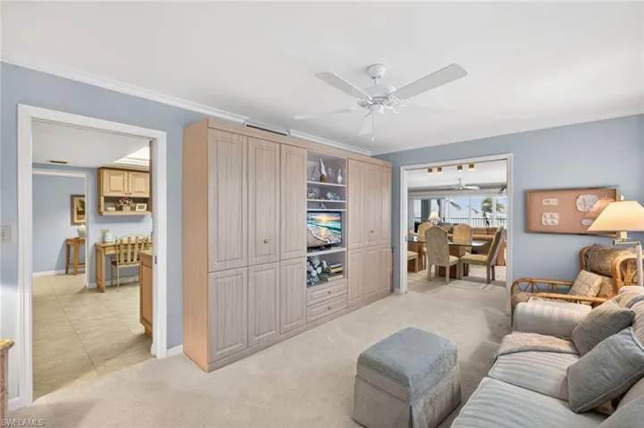 Den featuring light blue walls, a ceiling fan, and carpeted flooring