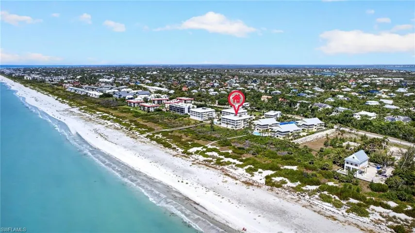 Aerial view showcasing the property's proximity to a sandy beach and turquoise water
